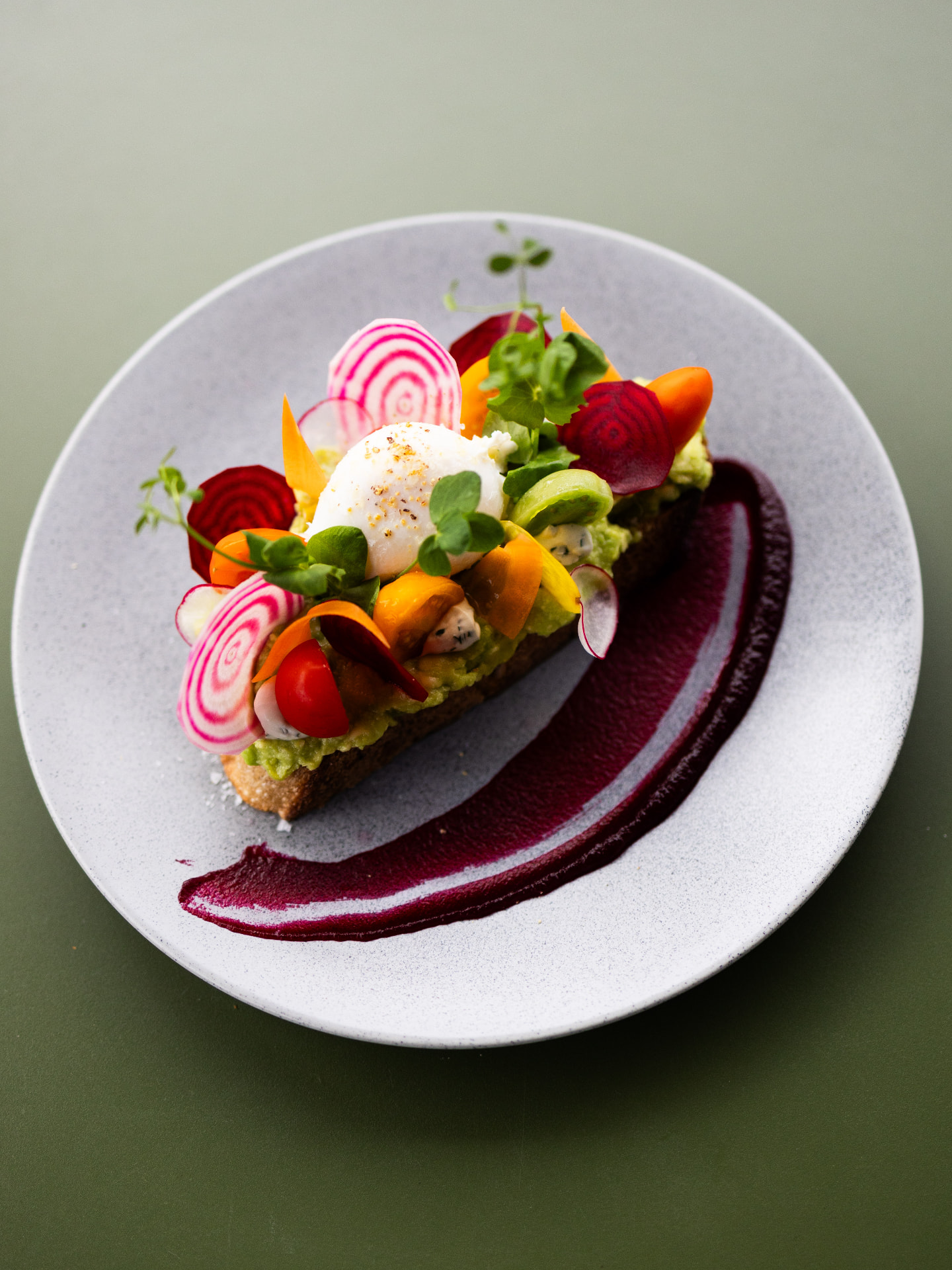 Avocadotoast med posert egg, beteer og småtomater på prikket tallerken